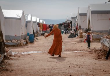 woman standing alone in the middle of tent homes in the desert. 